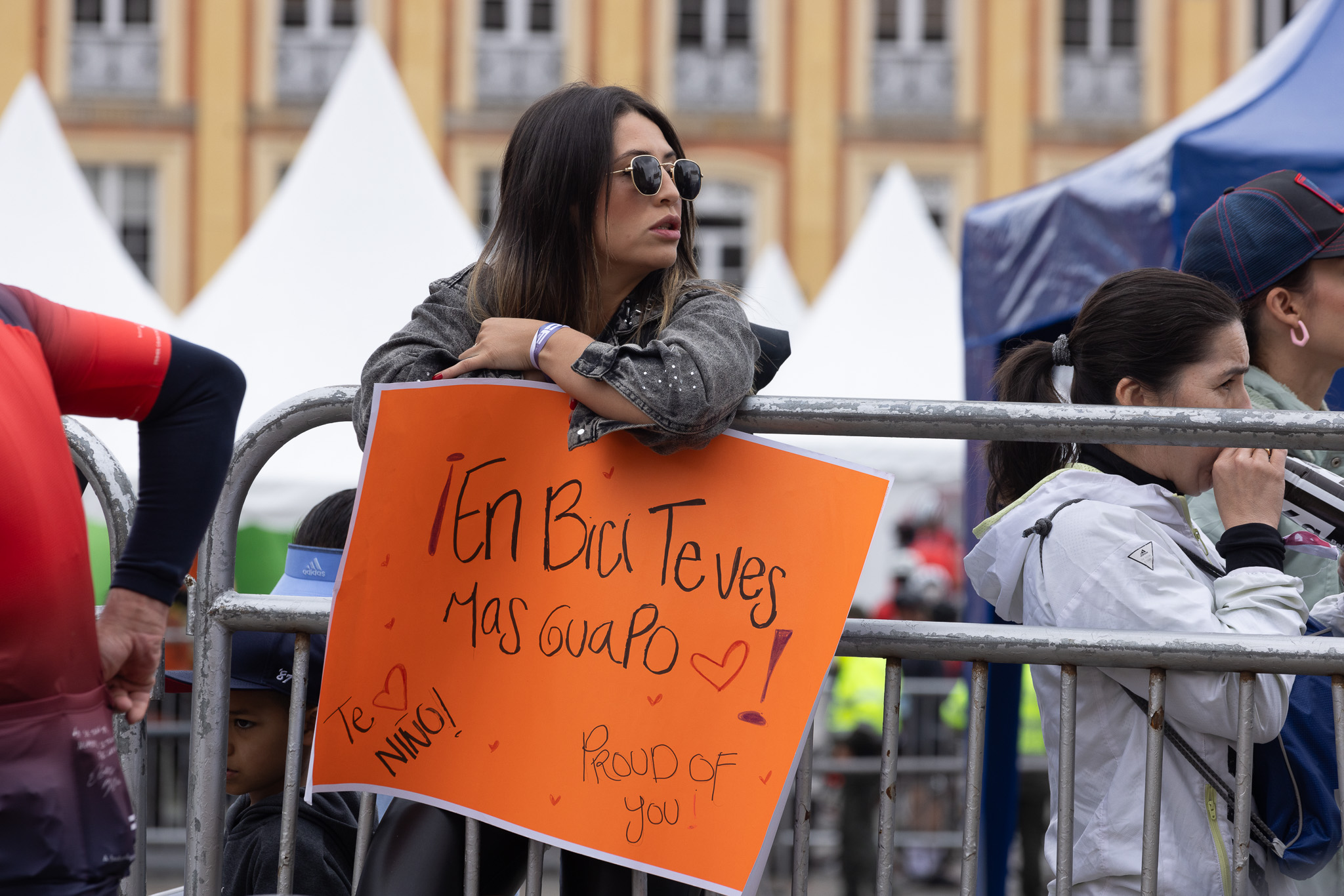 Foto de una joven con una cartelera animando a los ciclistas