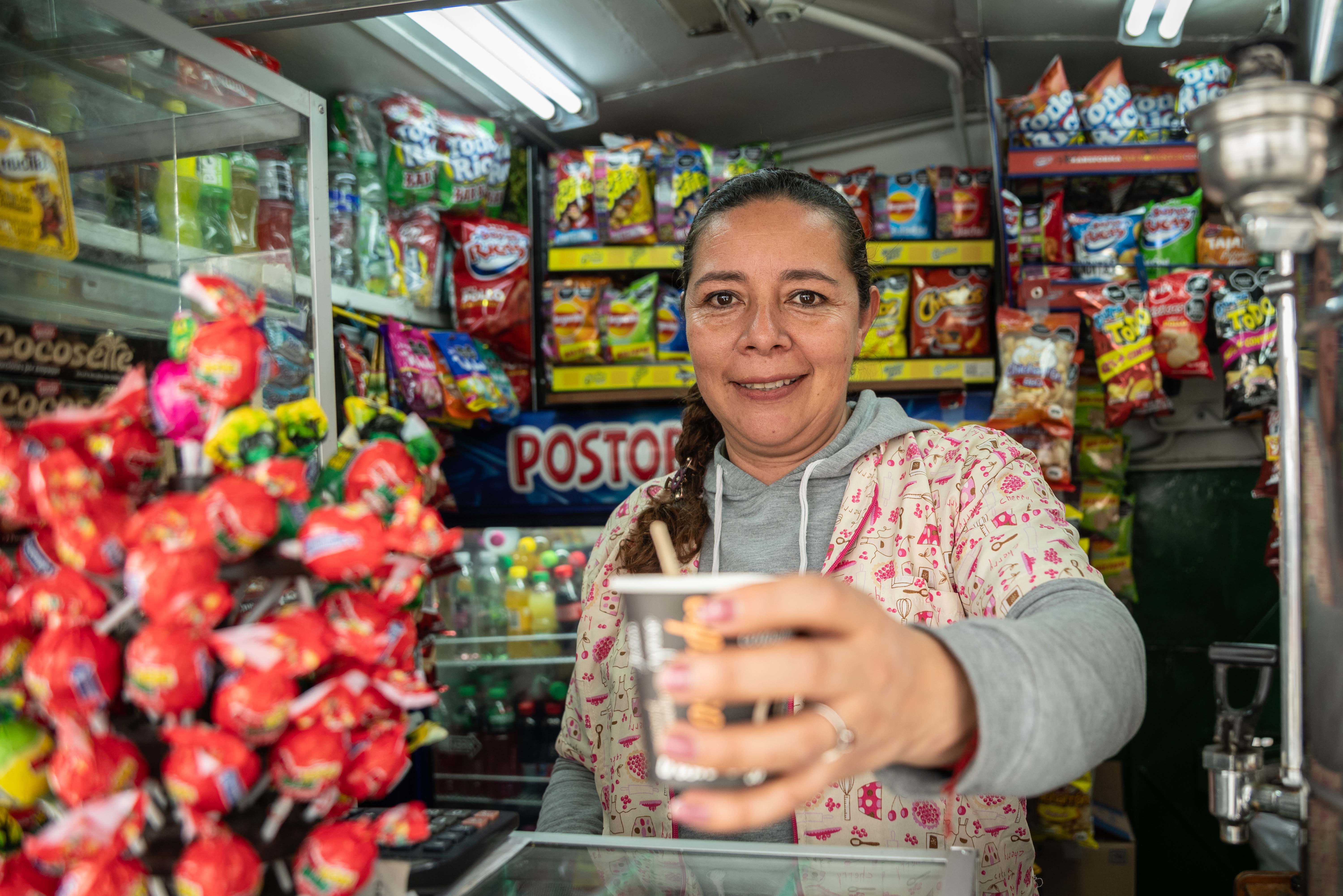 Foto de un joven soriendo ofreciendo un cono de helado.