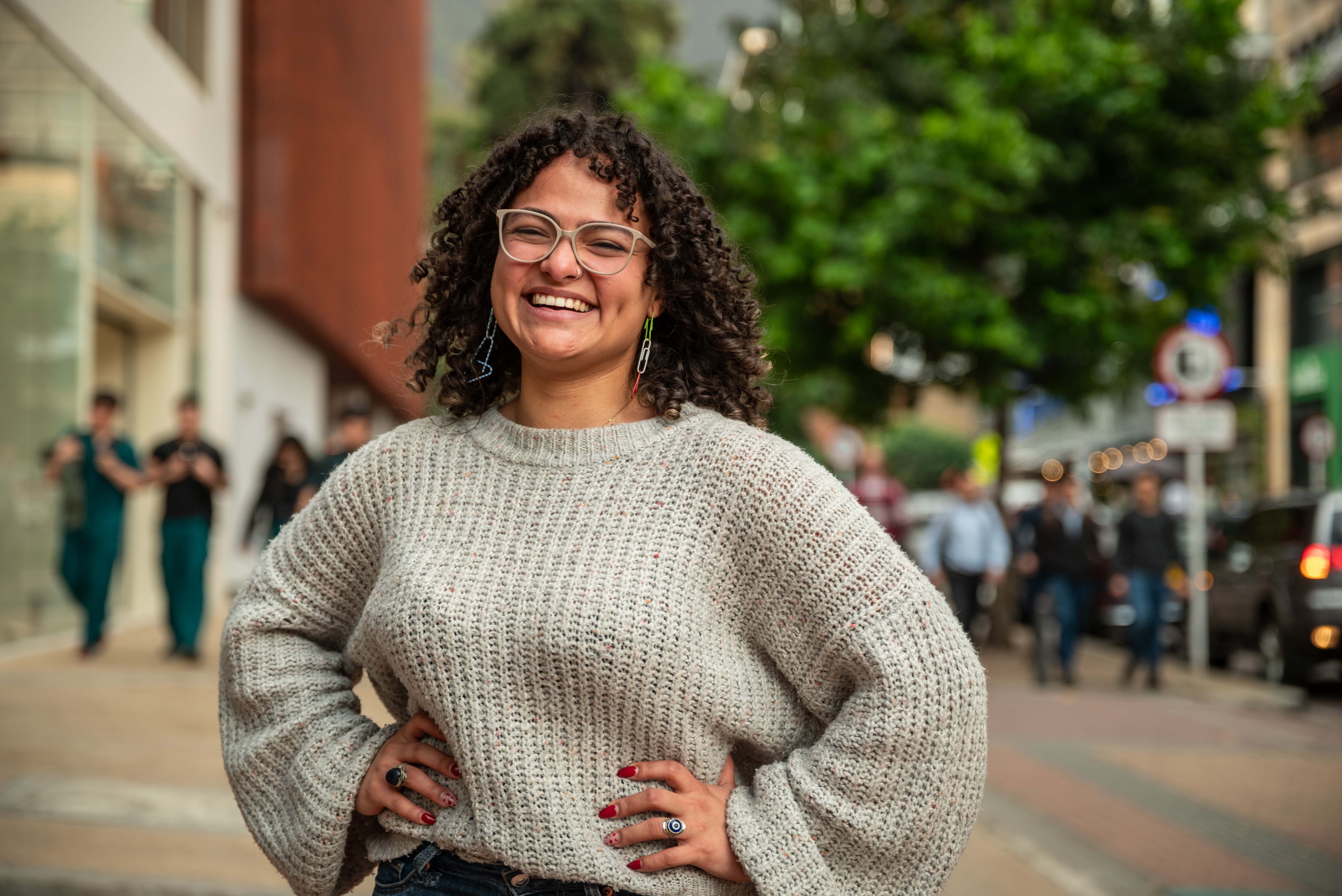 Foto de una mujer joven de cabello crespo y oscuro, de piel morena, sonrriendo