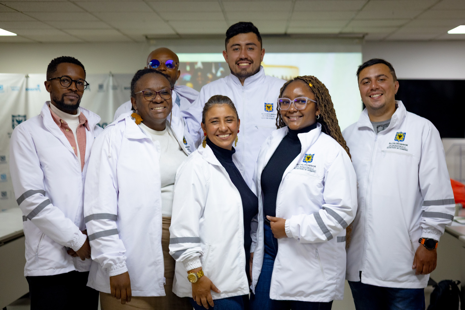 Foto del equipo de funcionarios de chaquetas blancas sonriendo