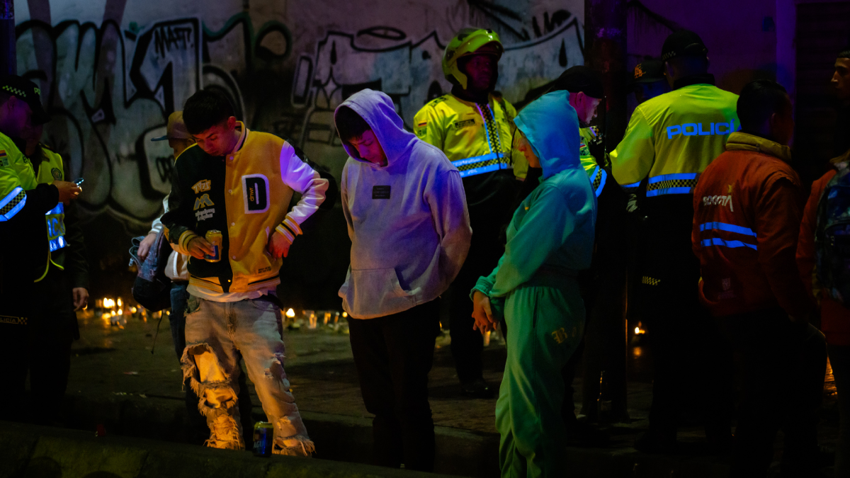 Foto de tres jovenes dos hombres y una mujer mirando las velas en la calle