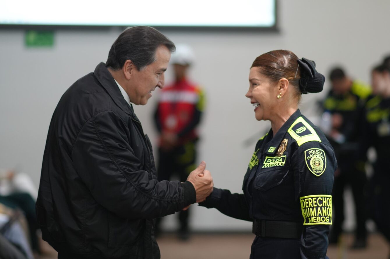 Foto de un hombre sonriendo dandole la mano a una mujer policia la cual tambien sonrie