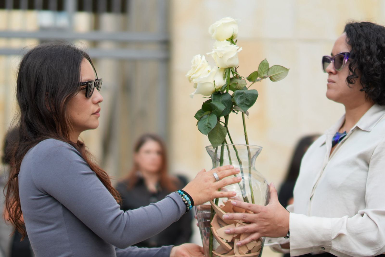 Foto de dos mujeres intercambiando una flor blanca.