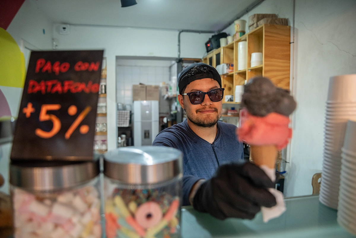 Foto de un joven soriendo ofreciendo un cono de helado.