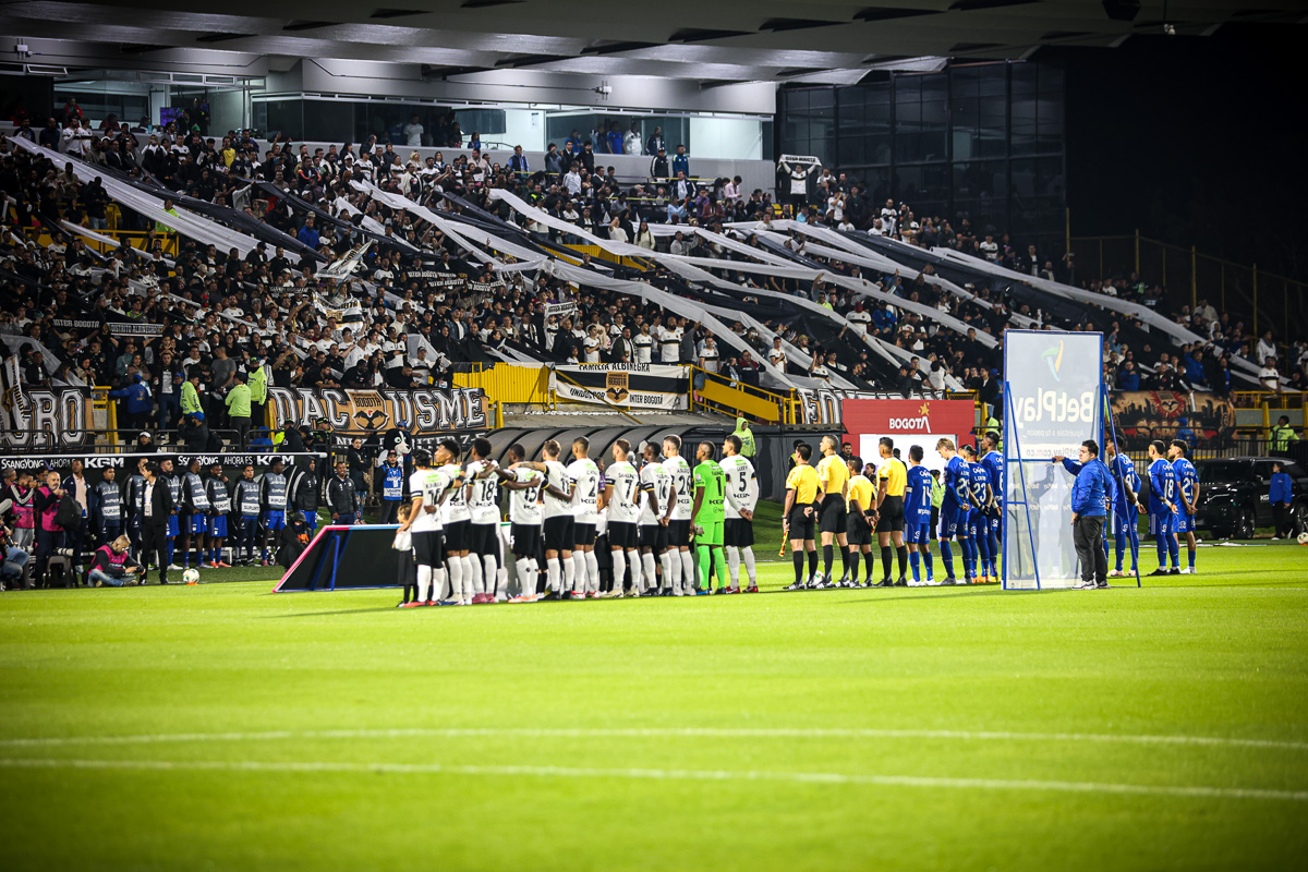 Fotografía de un estadio lleno y los equipos de fútbol ordenados