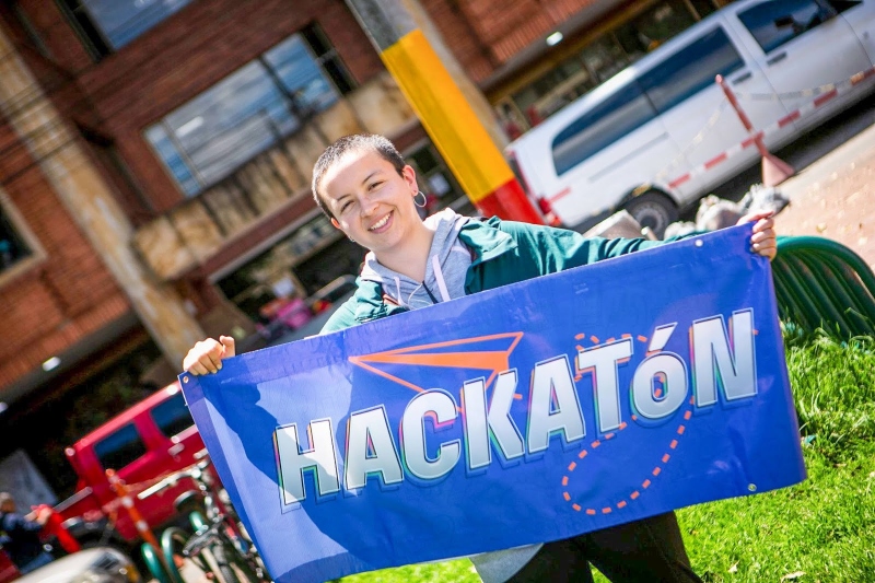 Foto de una mujer joven con un banner que dice Hackatón