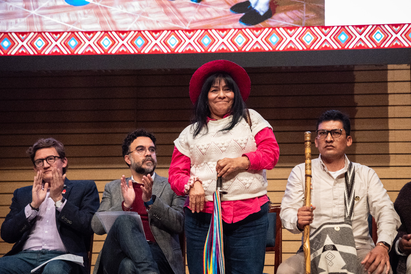 Foto de varias personas de los pueblos indígenas, se destaca una mujer indígena que se encuentra de pié.