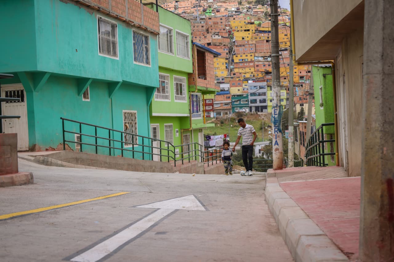 Foto de un adulto tomando la mano de su hijo caminando por uno de los nuevos tramos pavimentados