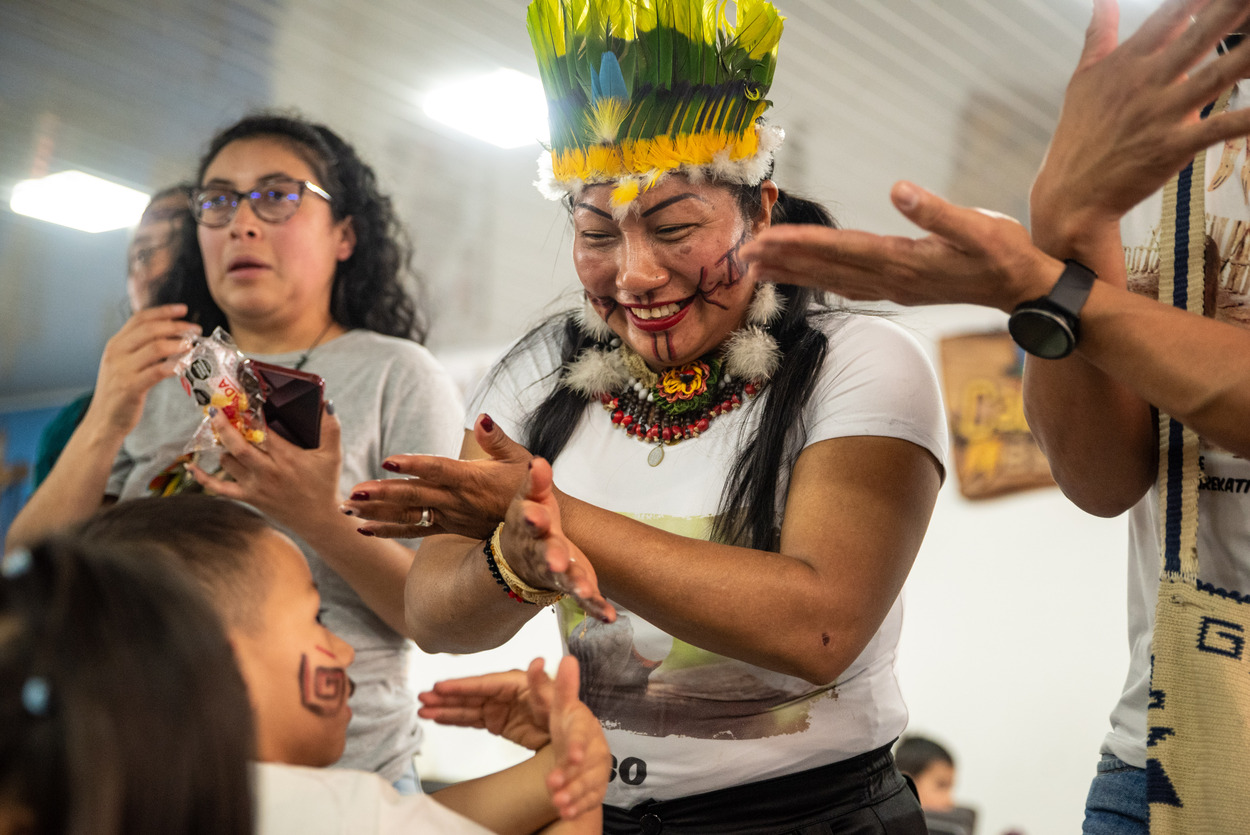 Foto de una mujer indigena sonriendo, jugando con un niño indigena