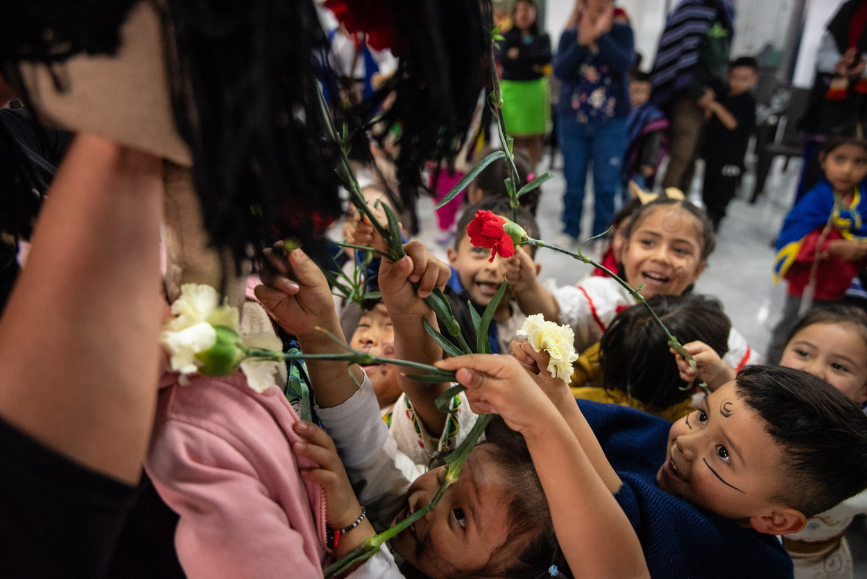 Foto de varias(os) niñas y niños sonriendo y dando rosas