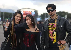 Tres jóvenes, dos mujeres y un hombre y de fondo el escenario de Rock al Parque 2025 en la tarde