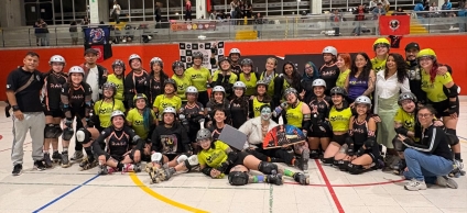 Participantes de un torneo de roller derby posan en grupo dentro de un escenario deportivo, con uniformes, cascos y patines, en un ambiente de celebración, integración y compañerismo.