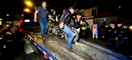Se encuentra la comunidad en la noche y unas personas sobre una grua bajando una moto