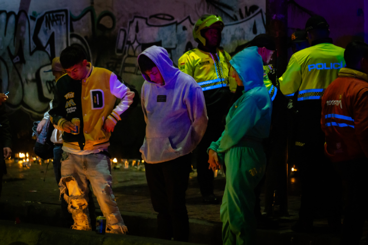 Foto de tres jovenes dos hombres y una mujer mirando las velas en la calle
