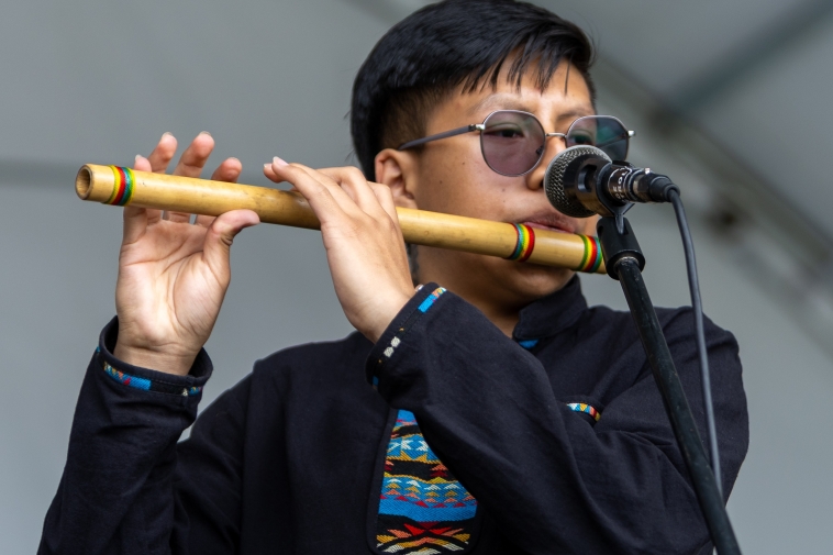Foto de un joven indígena interpretando una flauta