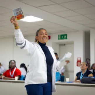 Fotografía de una mujer con chaqueta blanca dirigiendose a la audiencia