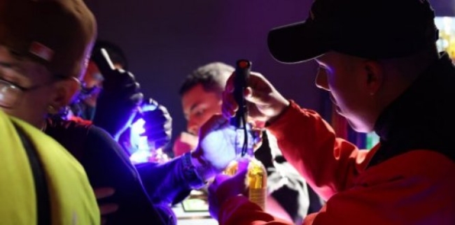 Foto de personas llenando botellas con licor