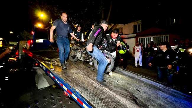 Se encuentra la comunidad en la noche y unas personas sobre una grua bajando una moto