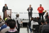 La imagen muestra un encuentro institucional con participación de la comunidad. En el escenario, varios representantes intervienen ante los asistentes durante una jornada de diálogo, mientras el público sigue la presentación desde el auditorio.